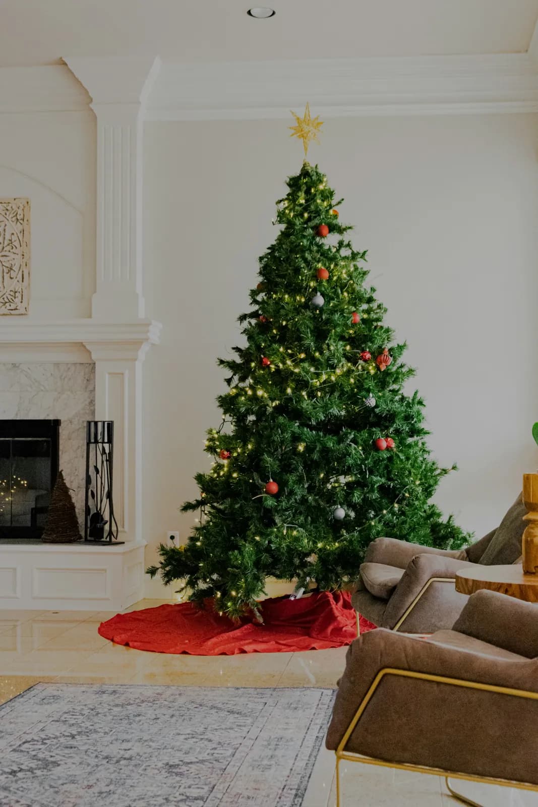 A tall decorated fir on a red tree skirt beside a window